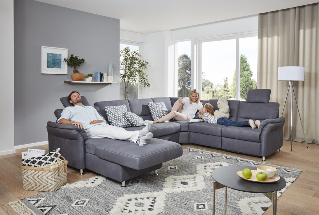 Familie entspannt auf einem grauen Sofa in einem modernen Wohnzimmer.