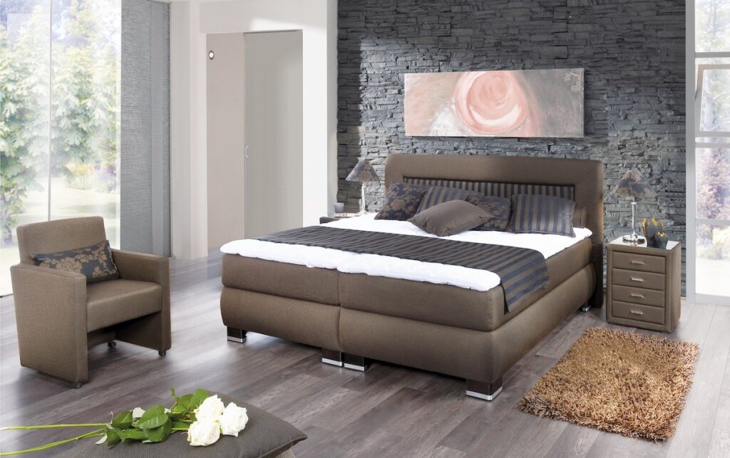 Braunes Boxspirngbett mit Nachtisch und einem Sessel
