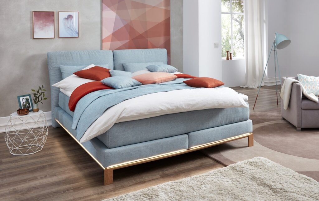 Gemütliches Doppelbett in Blau mit orangenen Kissen