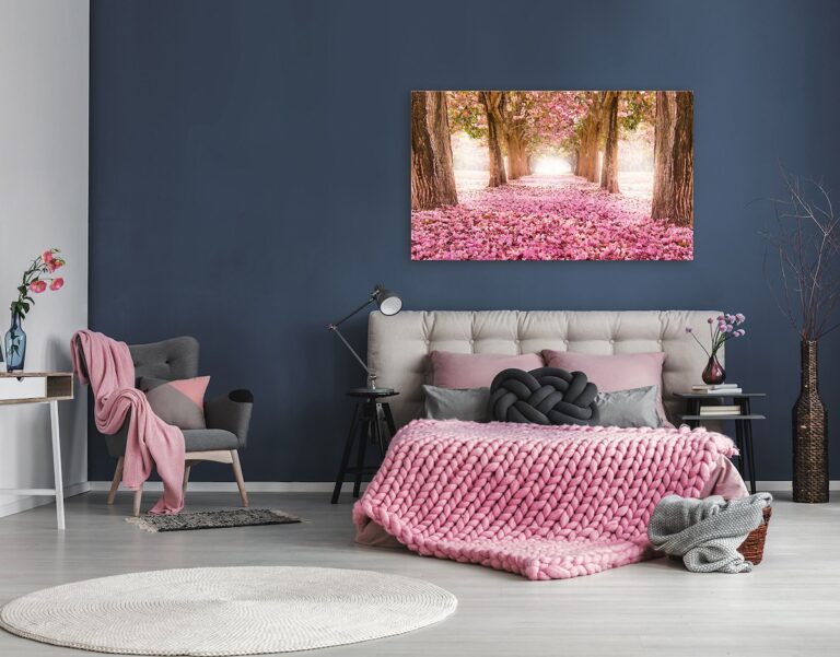 Rosa Schlafzimmer mit einem großen Leinwanddruck eines von blühenden Bäumen gesäumten Weges und einer grob gestrickten Decke.