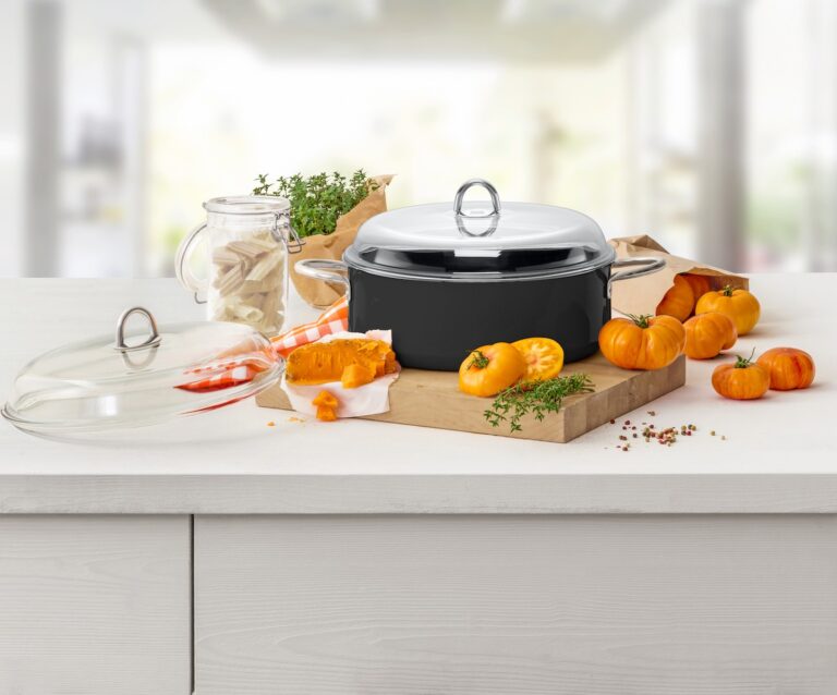 Grauer Topf auf einem Holzschneidebrett mit orangenen Tomaten