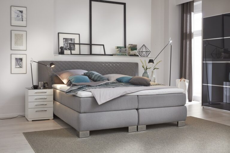 Graues umgepolstertes Bett mit weißen Nachttisch