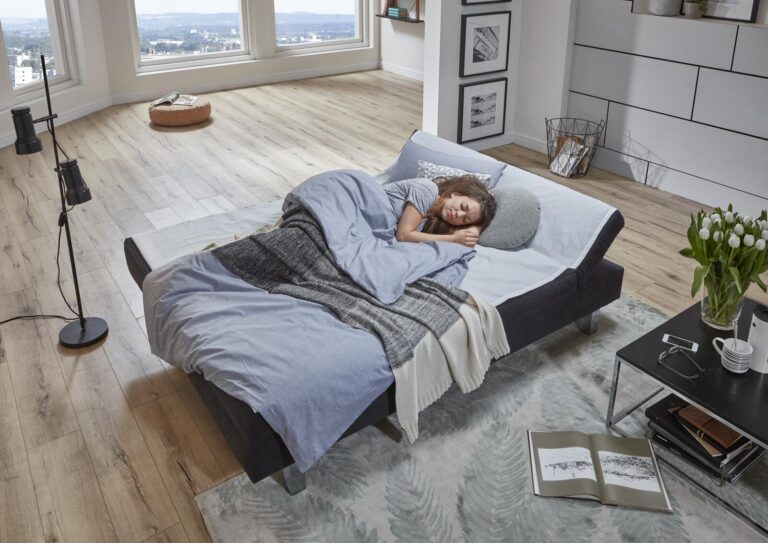 Frau schläft tief und fest auf einem bequemen Schlafsofa in einem modernen Apartment.