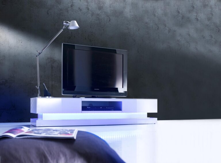 Moderner weißer TV-Ständer mit LED-Beleuchtung, der einen Flachbildfernseher in Szene setzt.