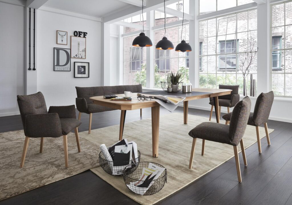 Modernes Esszimmer mit Holztisch, Sesseln und Pendelleuchten.