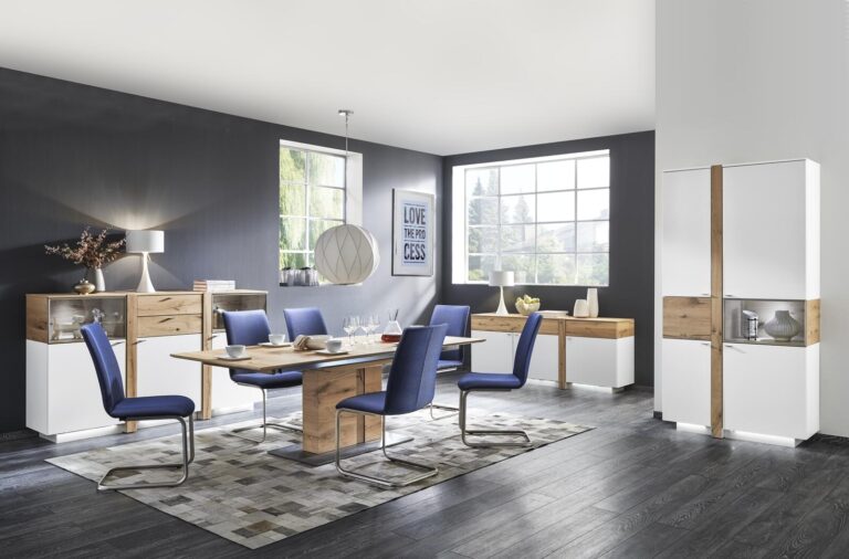Modernes Esszimmer mit Holztisch, blauen Stühlen und weißen Schränken. Sichtbares Kunstwerk „Love the Process“.