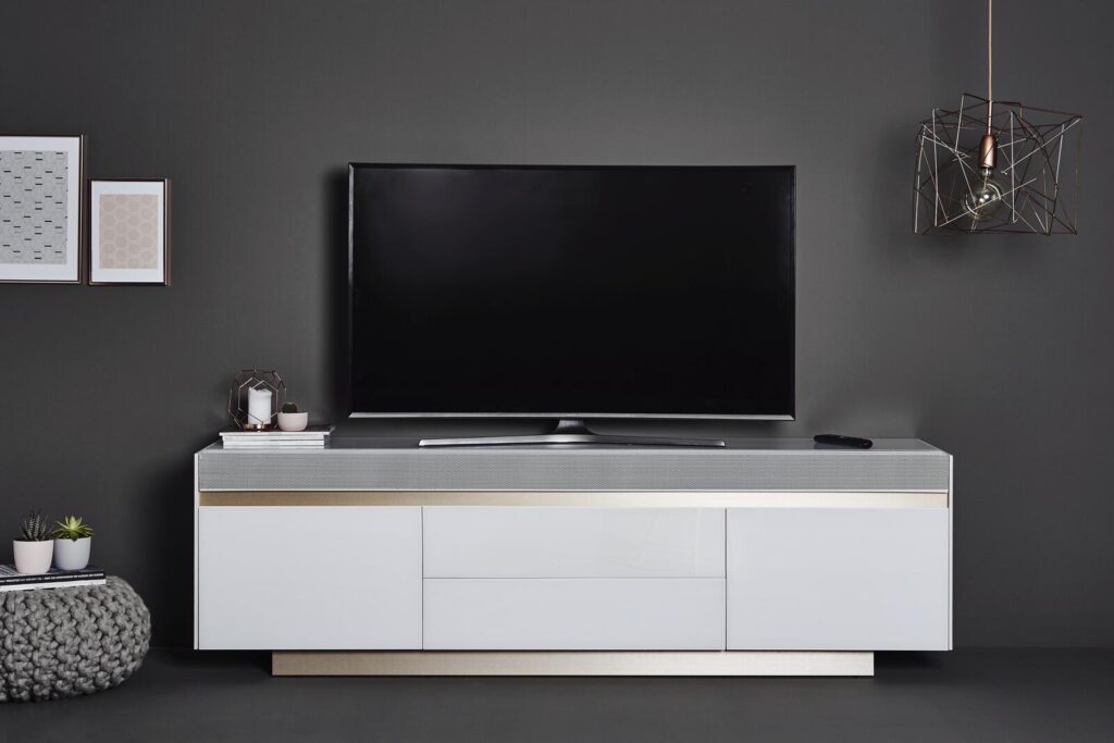 Moderne weiße Medienkonsole mit Fernseher, Soundbar und Dekor.