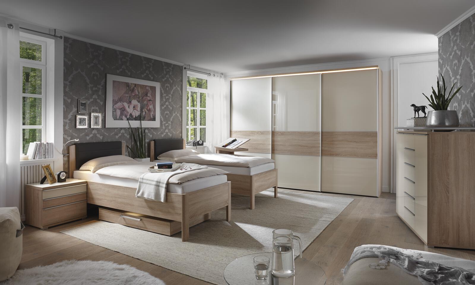 Modernes Schlafzimmer mit zwei Einzelbetten, Schiebetürenschrank und hellen Holzmöbeln.