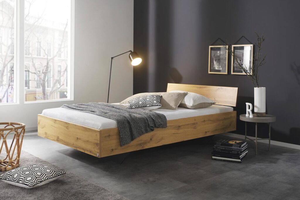 Modernes Plattformbett aus Eiche mit grauer Decke und Kissen in einem stilvollen Schlafzimmer.