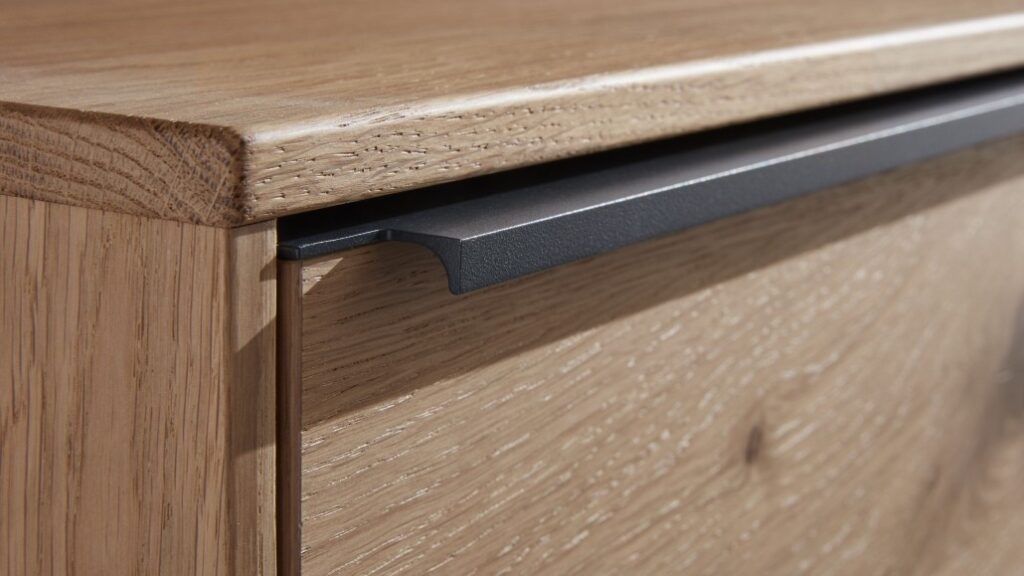 Nahaufnahme einer modernen Holzschublade mit einem eleganten, dunkelgrauen Griff.