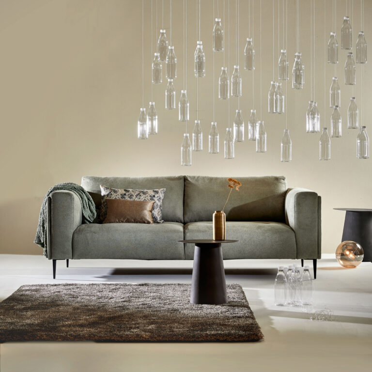 Modernes, salbeigrünes Sofa mit flaschenförmigen Pendelleuchten und Zottelteppich.