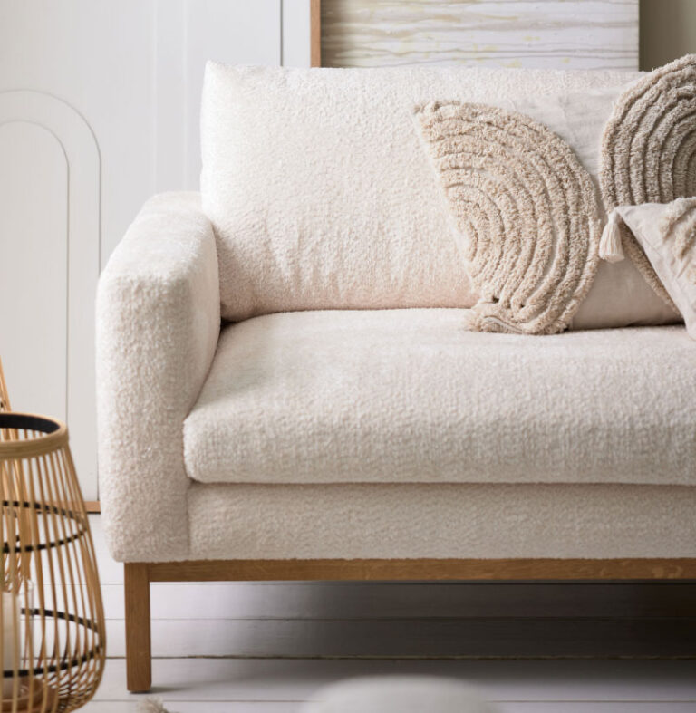 Cremefarbenes Bouclé-Sofa mit beigefarbenen strukturierten Kissen.