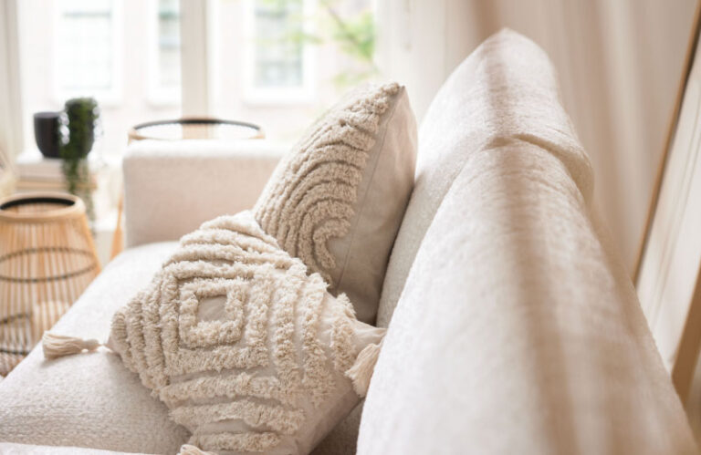 Cremefarbenes Sofa mit strukturierten Kissen. Gemütliche Wohnzimmereinrichtung.