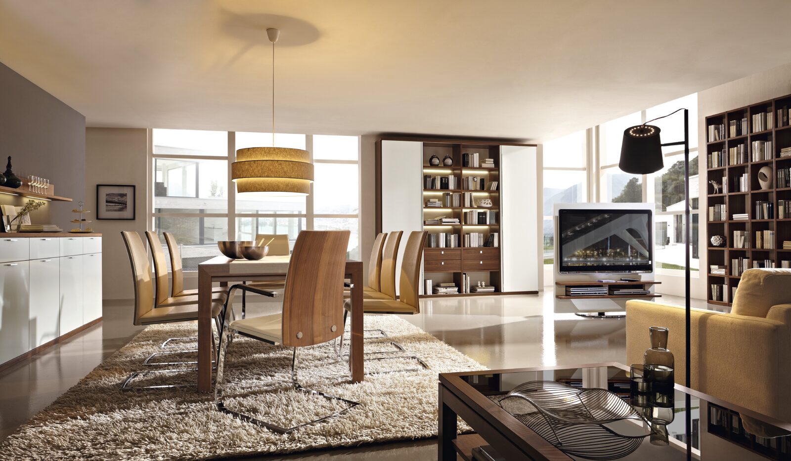 Modern living room and dining area featuring wooden furniture and a large flat-screen TV. The Varianta Studio at Interliving Boer.