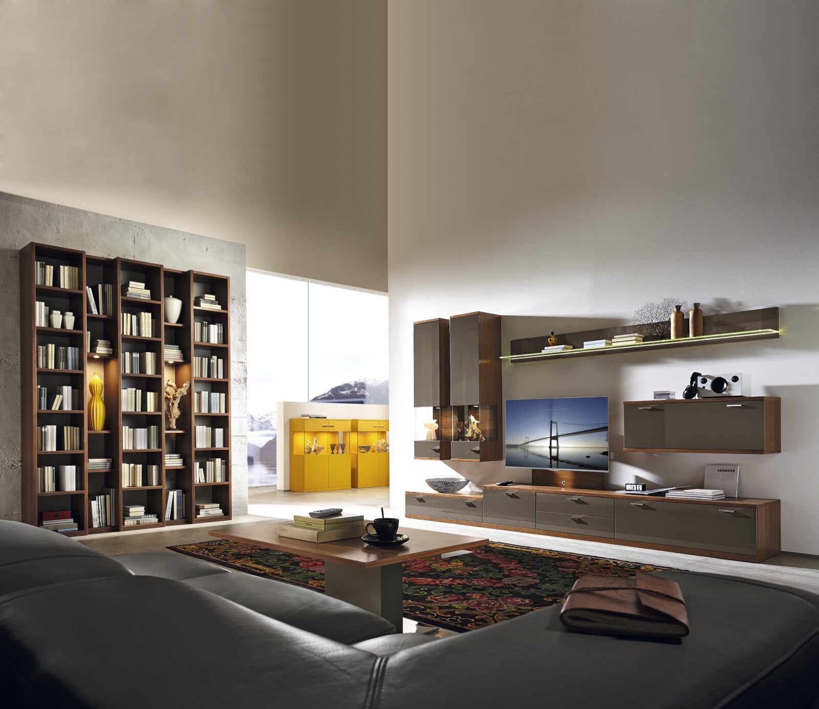 Modern living room with bookcases, media console, and leather sofa. New Varianta Studio at Interliving Boer.