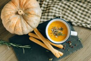 Kürbissuppe mit Kernen und Rosmarin garniert, serviert mit Grissini. Perfekt zum Erntedankfest.