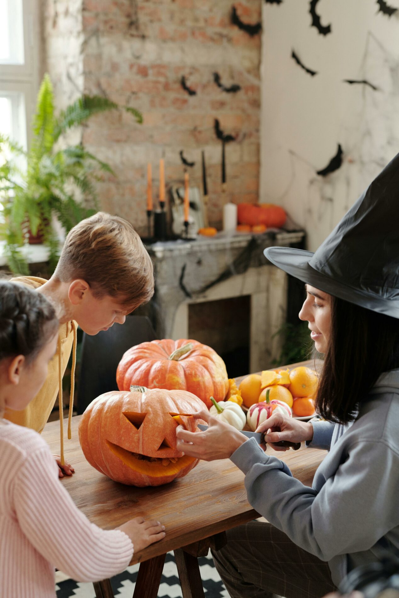 Family carving pumpkins for Halloween. Kids and mom enjoy fall festivities.