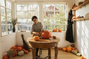 Frau schnitzt Kürbisse für Halloween. Fröhliches Halloween!