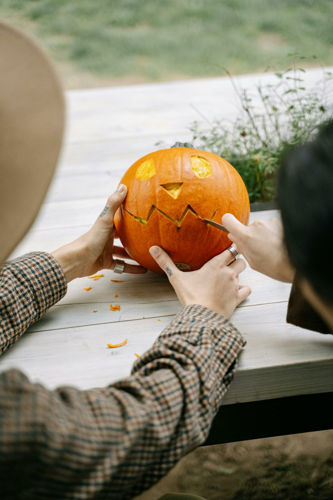 Two people carving a Halloween pumpkin, creating a jack-o'-lantern face.
