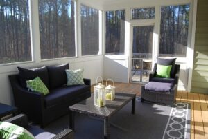 Gemütliche, abgeschirmte Veranda mit Korbmöbeln, Laternen und grünen Kissen, perfekt für den Winter.