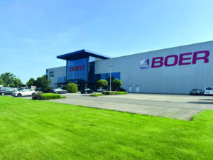 Großes Industriegebäude mit „BOER“-Beschilderung und geparkten Autos
