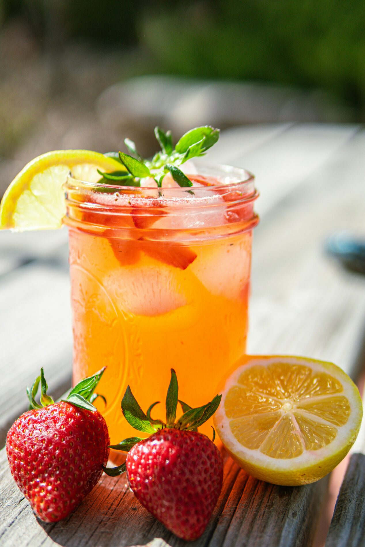 Einmachglas mit erfrischender Erdbeerlimonade mit Eis, Zitronenscheiben und frischen Erdbeeren. Das perfekte Sommergetränk!