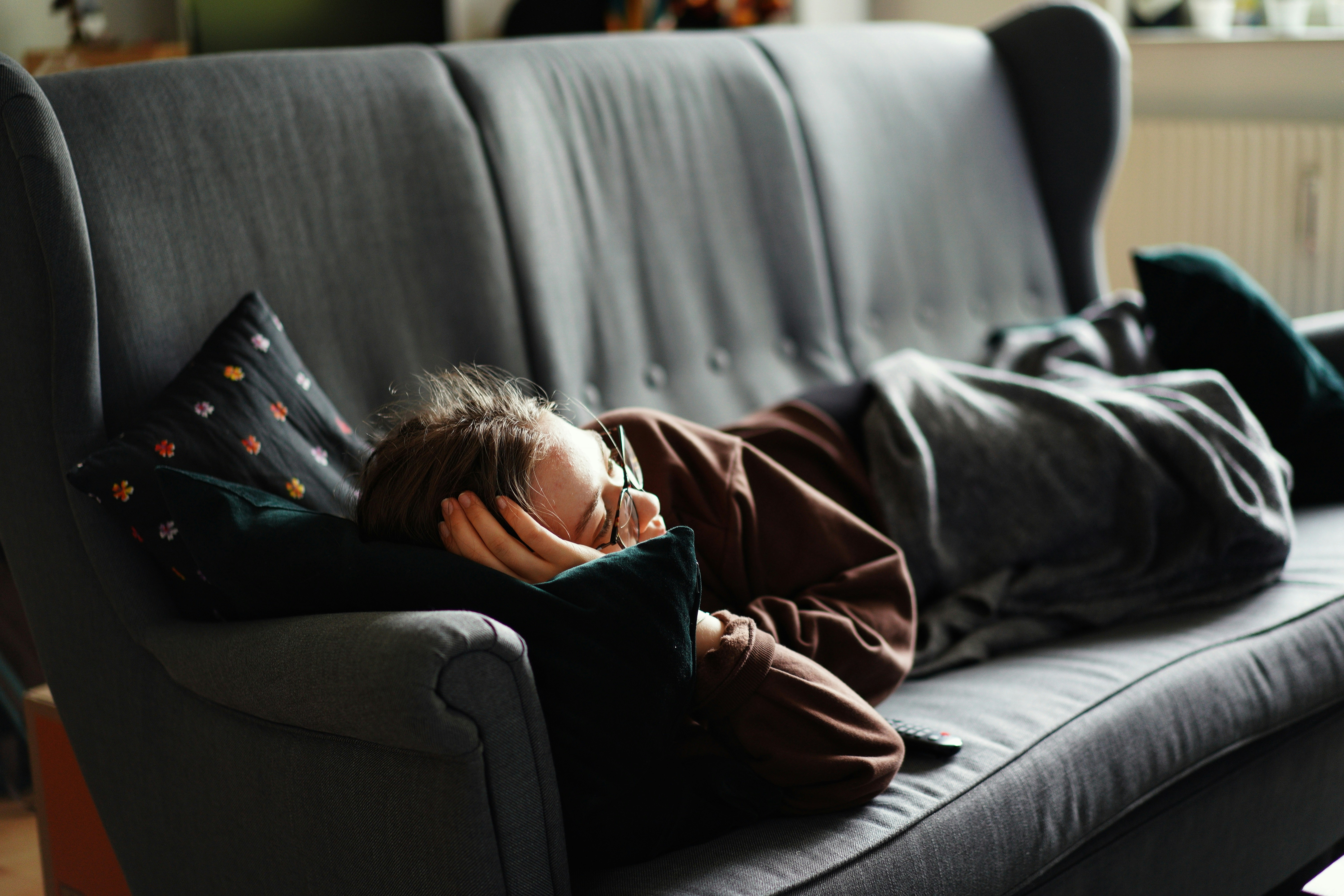 Person ruht auf einer grauen Couch und übt Achtsamkeit im Alltag