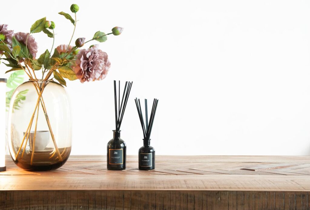 Dekorative Duftstäbchen neben Blumen in Vase auf einem Holztisch.