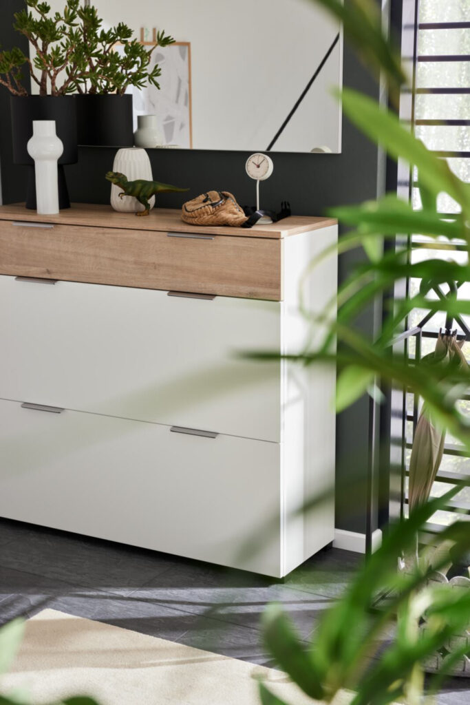 Moderner Schuhschrank mit Holzplatte, weißen Schubladen, Deko und Spiegel.