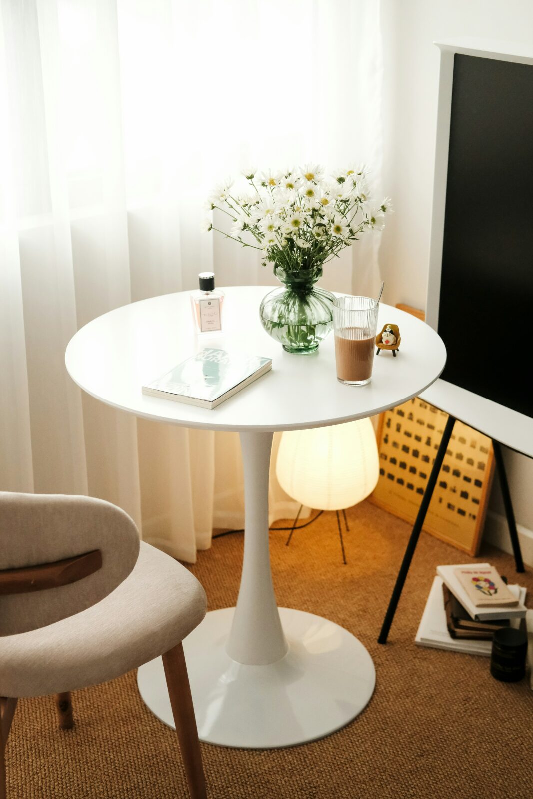 Dekorativer Tisch mit Blumen, Buch und Getränk. Möbel-Inspiration für Interliving Boer im November.