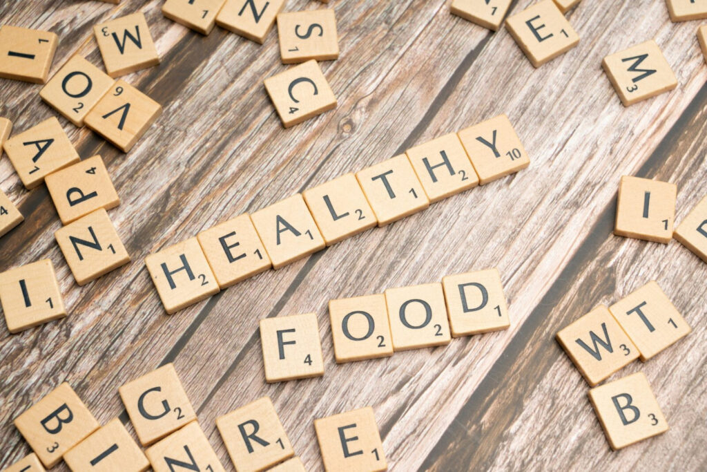 Healthy Food" aus Scrabble-Steinen auf Holz. Gesunde Vorsätze fürs neue Jahr, Ernährung.