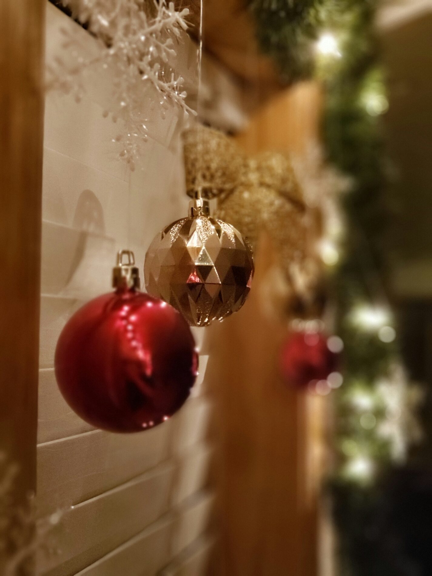 Weihnachtsdekoration: Rote und goldene Christbaumkugeln vor festlicher Girlande.