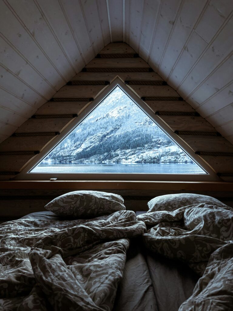Gemütliches Schlafzimmer im Winter mit Blick auf verschneite Berge. Schlafzimmer-Check für besseren Schlaf.