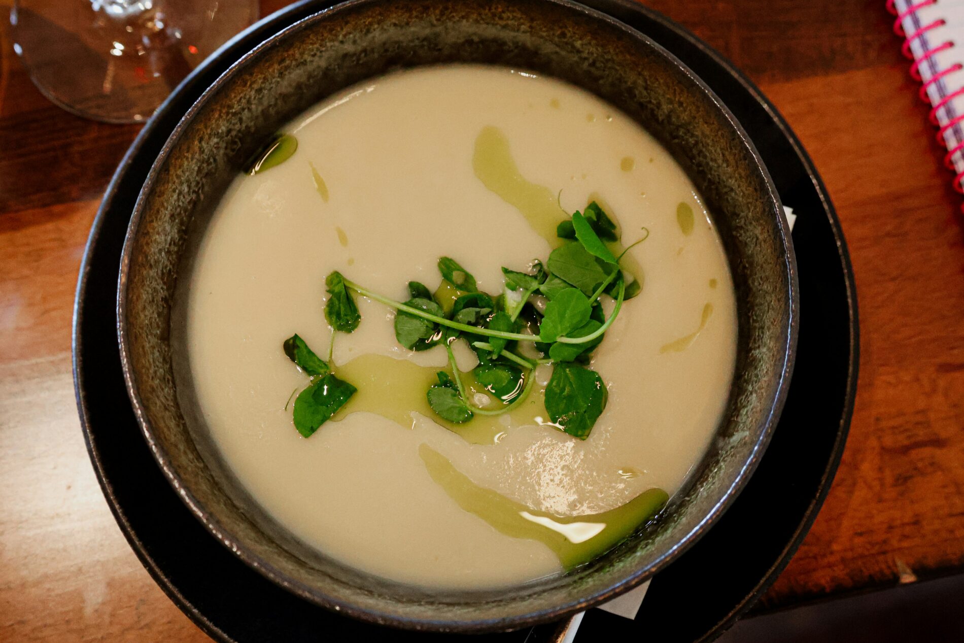 Cremige Gemüsesuppe mit frischen Kräutern in dunkler Schale. Saisonales Gemüse Rezept.